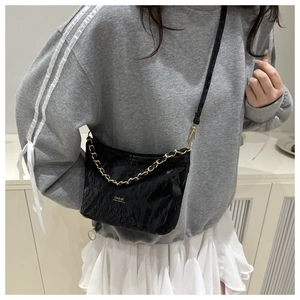 Détail d'un sac seau noir plissé avec bandoulière chaîne dorée et logo métallique