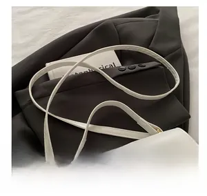 Détail du sac bandoulière en cuir PU blanc avec boucle en métal doré sur fond sombre