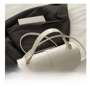 Détail d'un sac à main en cuir blanc avec boucles dorées et finitions métalliques