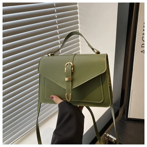 Detail of dark green envelope handbag with retro gold horseshoe clasp and leather handle