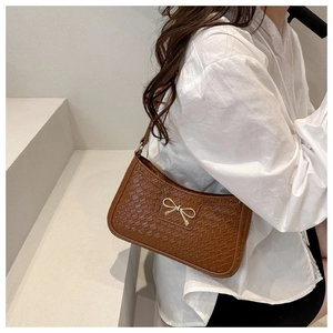 Close-up of deep brown woven texture leather shoulder bag with gold bow buckle