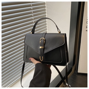 Detail of black rectangular crossbody bag with golden buckle and sleek leather texture