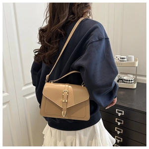 Detail of khaki leather handbag featuring gold buckle and elegant V-shaped flap cover