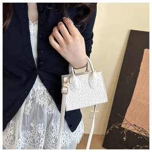 Close-up of white crocodile texture leather mini square bag with golden hardware