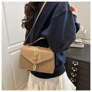 Detail of khaki leather shoulder bag featuring gold U-shaped metal buckle and texture