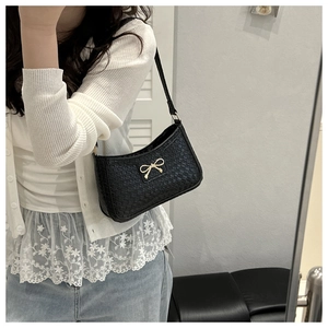 Detail of black woven texture leather bag with a vintage golden bow buckle accent