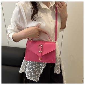 Détail du sac bandoulière fuchsia avec finitions dorées et texture cuir lisse