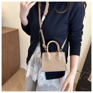 Close-up of beige woven faux leather texture and gold hardware on crossbody bag