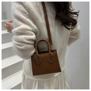 Detailed view of a brown woven mini tote bag shown on a model in a minimalist setting
