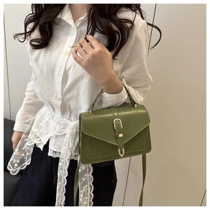 Detail of green PU leather crossbody bag with gold buckle hardware and top handle strap