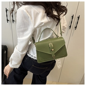 Détail du sac bandoulière carré vert fruit avec boucle en métal sur un jean bleu