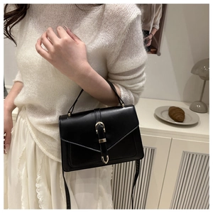 Détail du sac bandoulière vintage en cuir noir avec boucle en U dorée sur mannequin femme