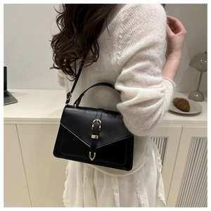 Vue latérale d'un sac à bandoulière vintage noir avec boucle dorée porté par un mannequin