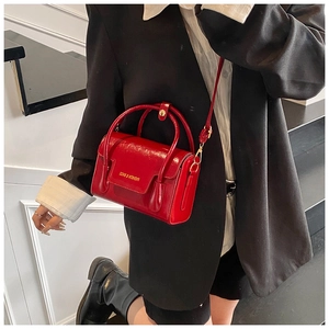 Detailed view of red glossy patent leather mini crossbody bag with gold fashion lettering