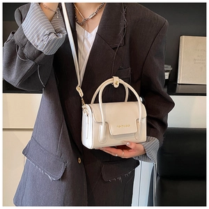 Detail of cream-colored square crossbody bag with Fashion & Bags lettering on textured flap