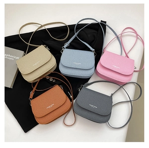 Flat lay of multiple stylish woven saddle bags in beige, blue, pink, brown, and grey colors