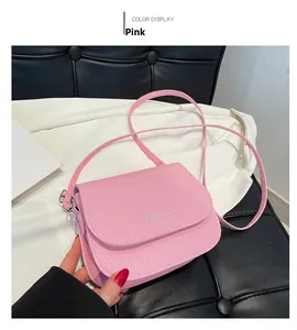 Detail of pink saddle bag with woven texture, silver logo, and thin shoulder strap