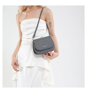 Close-up of a gray saddle bag with silver metal buckle on a model in a minimal studio