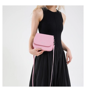 Detail of pink pebbled leather crossbody saddle bag with silver hardware on a model