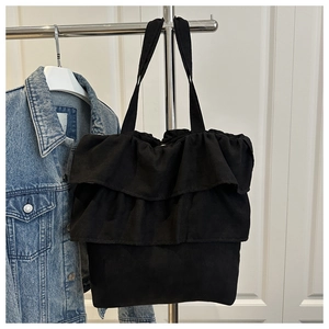 Close-up of black canvas tote bag featuring double ruffle pleats and a minimalist design