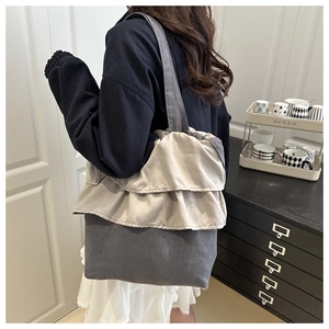 Detailed view of ruffle pleated grey fabric tote bag shown on model in a home setting