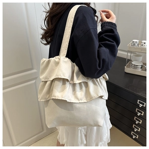 Close-up of pleated ruffle detailing on a large canvas tote bag in off-white finish