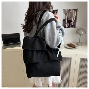 Detail of the black canvas tote bag showing the three-layer ruffle design and texture
