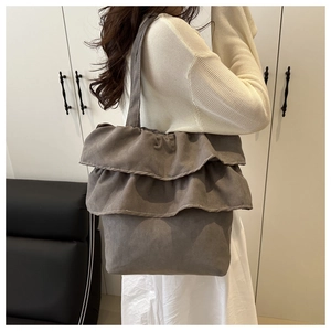 Detail of grey layered ruffle tote bag shown on model in a minimalist setting