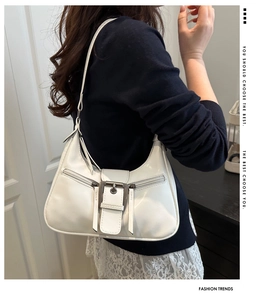 White glossy hobo bag with large metal buckle and dual zipper details in Y2K style