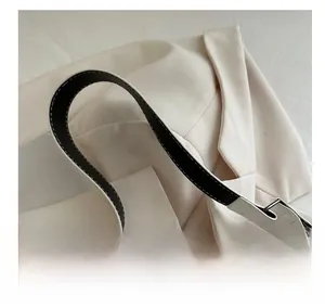 Detail of the white minimalist handbag showing the bicolor leather handle and silver metal hardware