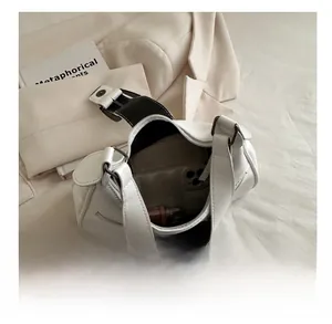 Internal view of a white leather handbag showing its capacity for phones and cosmetics