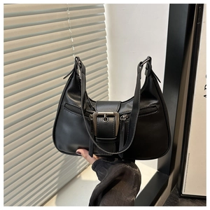 Detail of black matte leather crescent bag with vintage metal buckle and side zippers