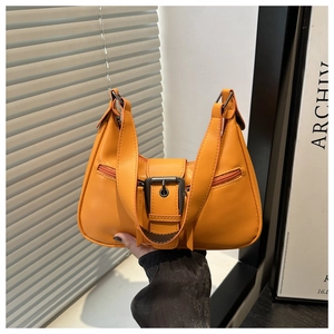 Detailed view of bright orange leather handbag with large vintage buckle and side zippers