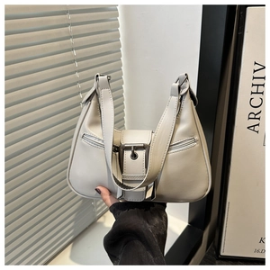 Detailed view of cream half-moon hobo bag with metal buckle and twin zipper pockets
