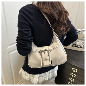 Detail of a vintage-style cream shoulder bag featuring retro metal buckle and zip pockets