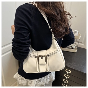 Close-up of a white leather crescent moon bag with a large metal buckle and strap