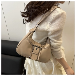 Close-up of beige crescent bag featuring decorative metal buckle and dual side zippers