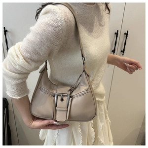 Detail of beige crescent underarm bag showing silver buckle and side zipper accents