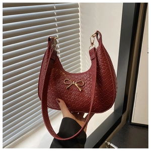 Detail of burgundy woven hobo bag with gold bow clasp and elegant textured finish