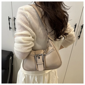 Close-up of cream faux leather shoulder bag with decorative metal buckle and zipper