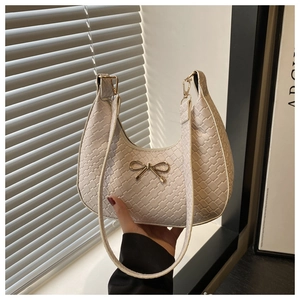 Close-up of cream-white woven texture shoulder bag with gold bow-knot hardware