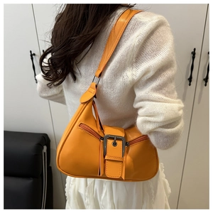 Close-up of bright orange PU leather shoulder bag with silver buckle and zippers