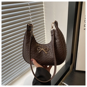Detail of brown woven hobo bag featuring a gold bow buckle and crescent shape