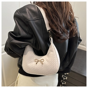 Detail of white hobo bag with crocodile texture and golden bow decoration on shoulder