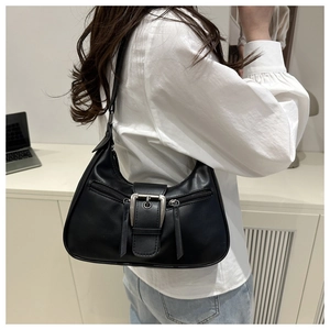 Detail of minimalist black underarm bag with silver buckles and zipper pockets