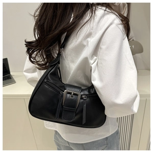 Close-up of black hobo bag featuring large metal buckle and smooth synthetic leather texture