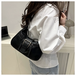 Detail of black leather underarm bag with silver buckle and side zipper pockets