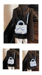 Close-up of light blue bow tote bag showing detailed texture and gold fashion lettering