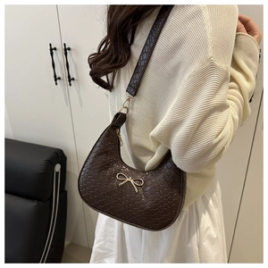 Close-up of dark brown crescent bag featuring woven texture and golden bow buckle