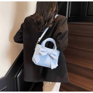 Macro view of light blue PU leather tote featuring a large bow and gold foil lettering